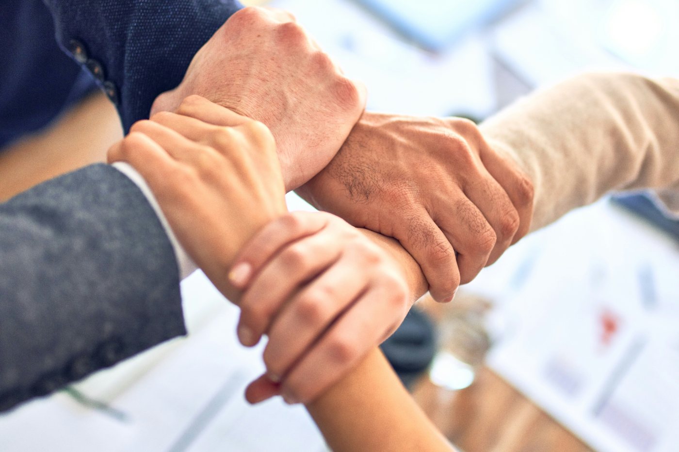 Four hands interlocked over a meeting table